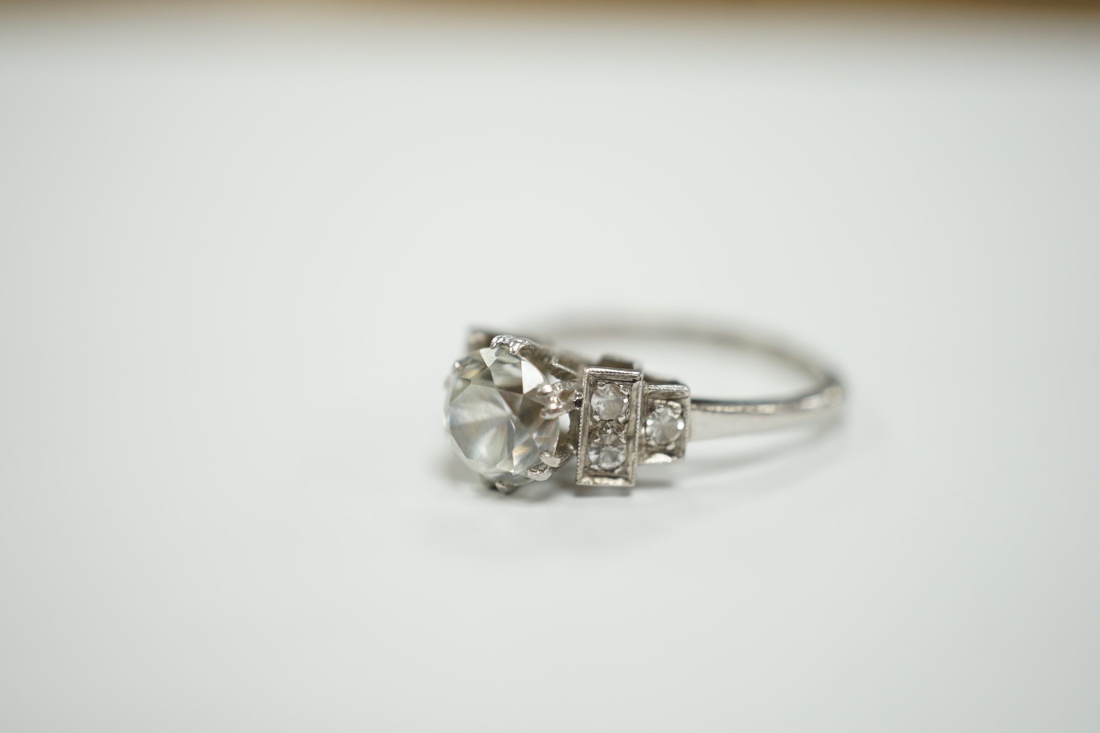 A mid 20th century white metal (stamped plat) and single stone white zircon? set ring, with simulated diamond set shoulders, size N, gross weight 4.3 grams.